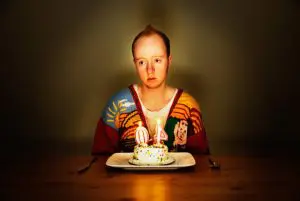 Photo of a person sitting sadly with a birthday cake