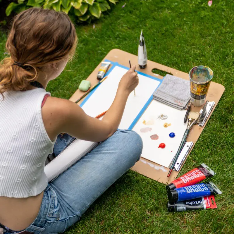 Someone sitting outside painting