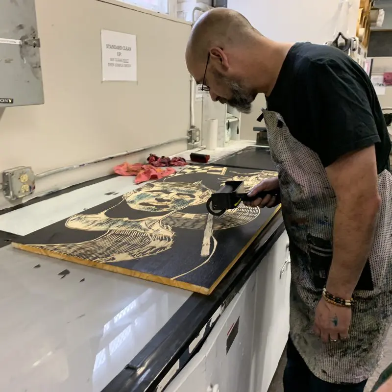 Person rolling ink on a wood block