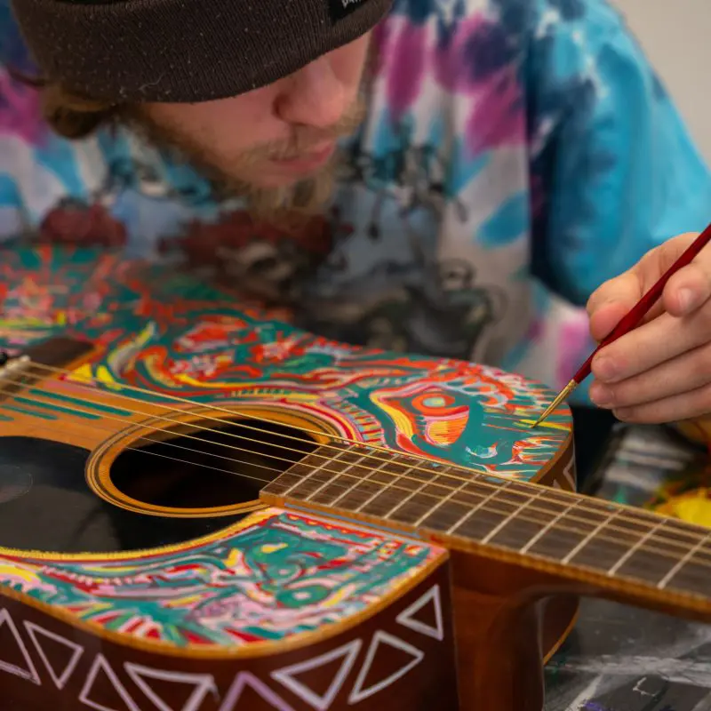 Person painting an acoustic guitar