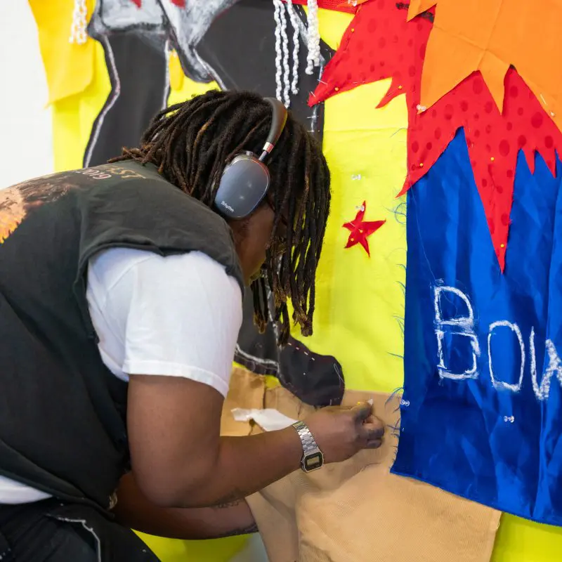 Student pinning fabric to a wall