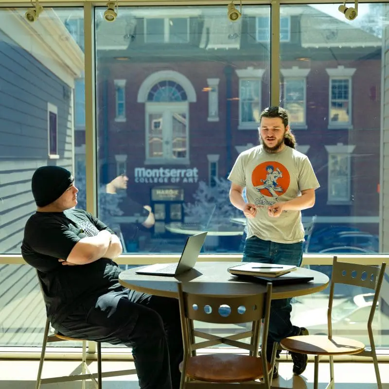 two students woking at a table in a sunny window