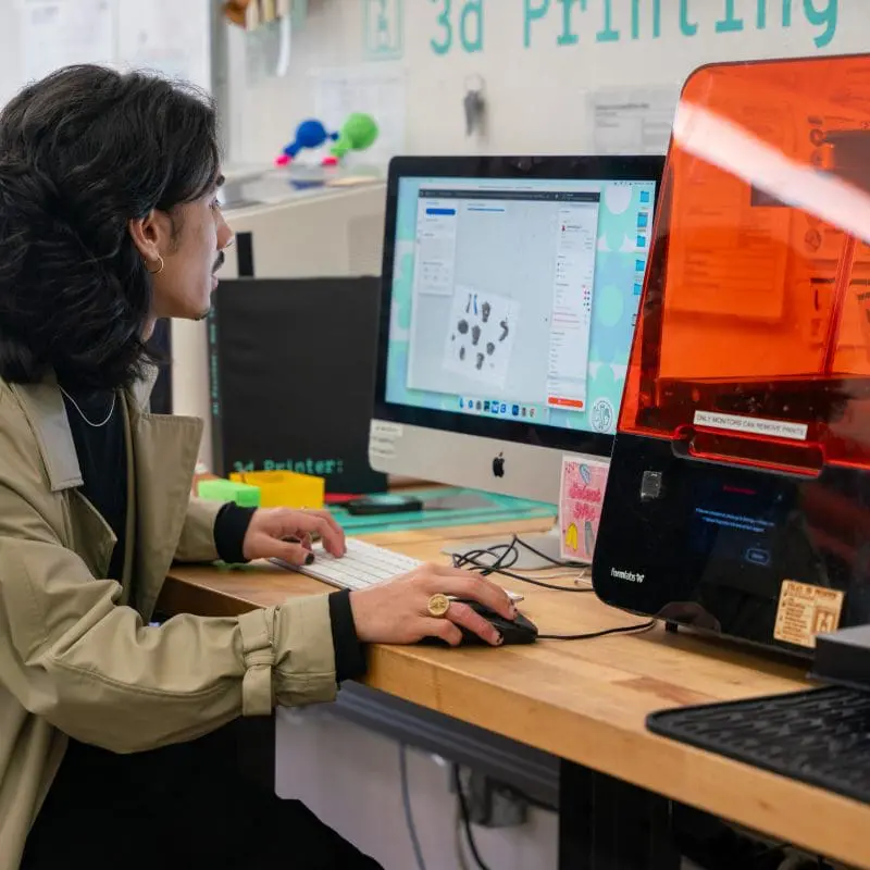 person working at a computer and 3D printer