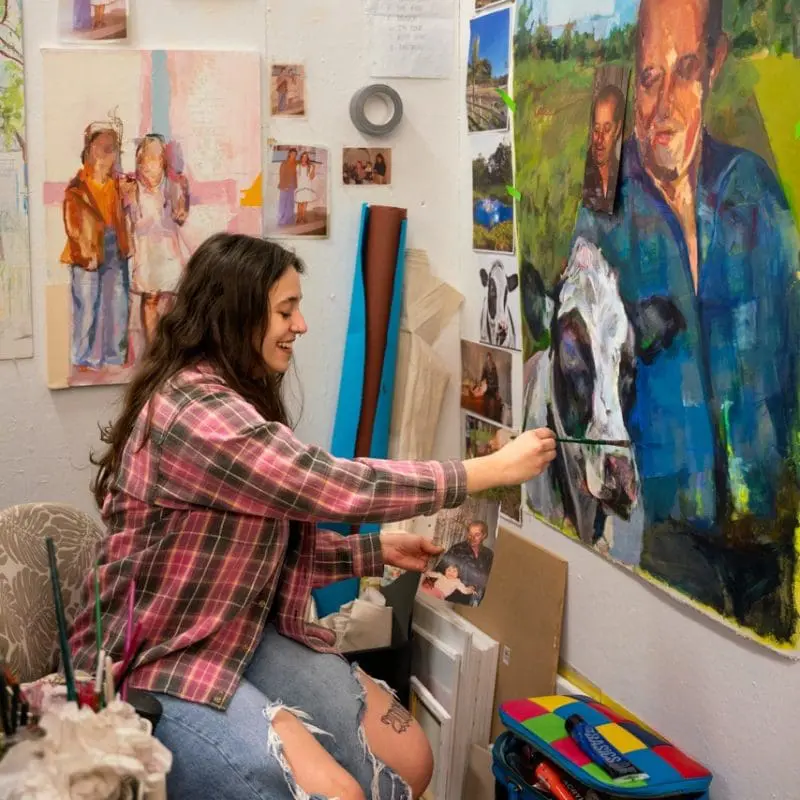 student smiling while painting in her studio