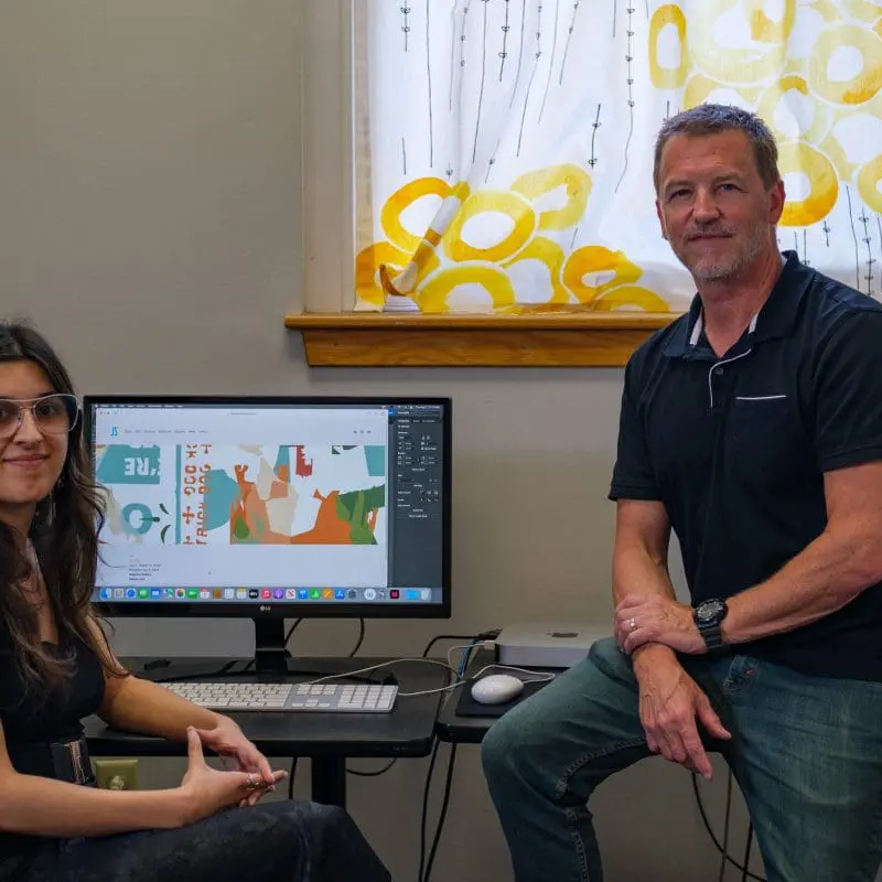 Photo of two people with a computer
