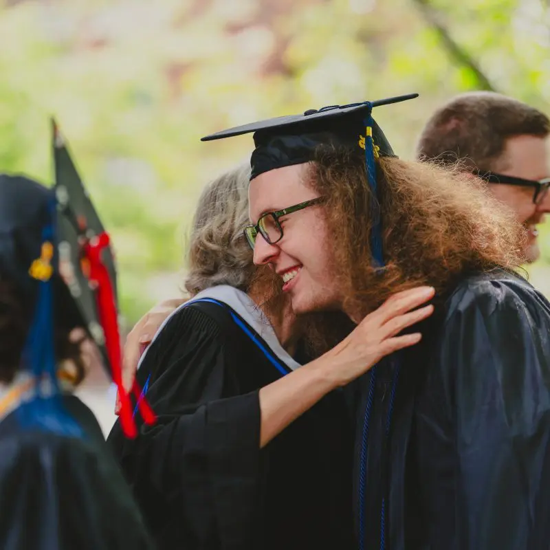 Graduates hugging faculty