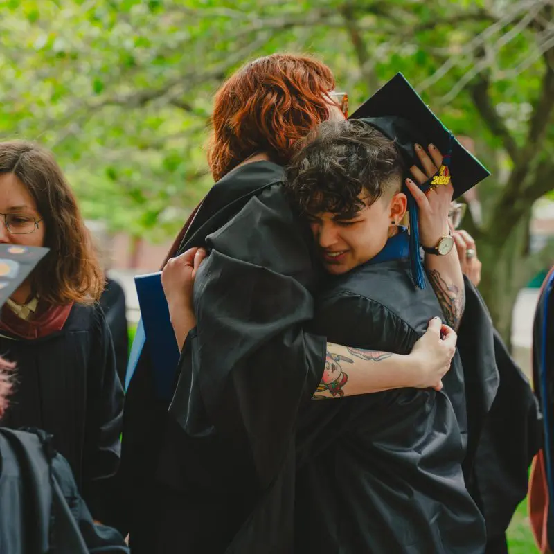 Graduates and faculty hugging