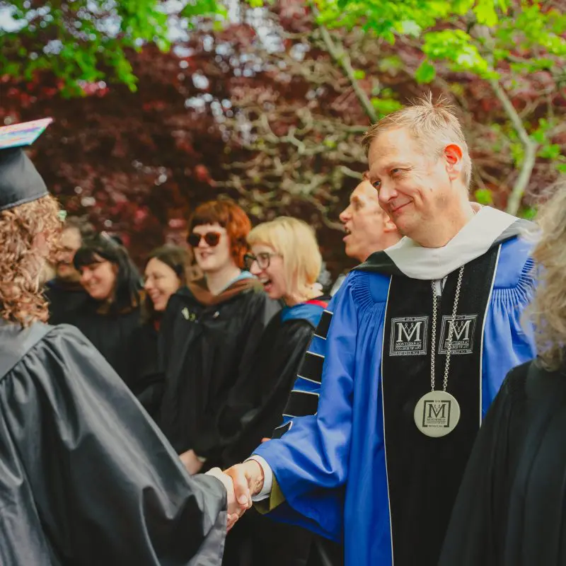 President Brian and graduates shaking hands