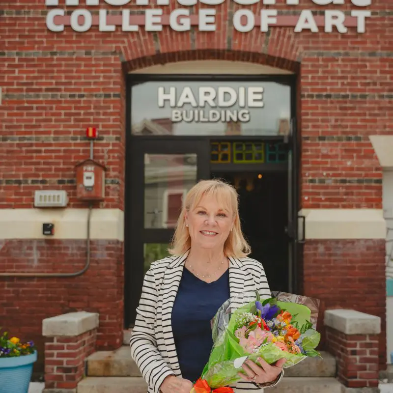 Jo holding flowers and standing in front of the Hardie Building