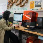 person sitting at a computer in the digital fabrication studio