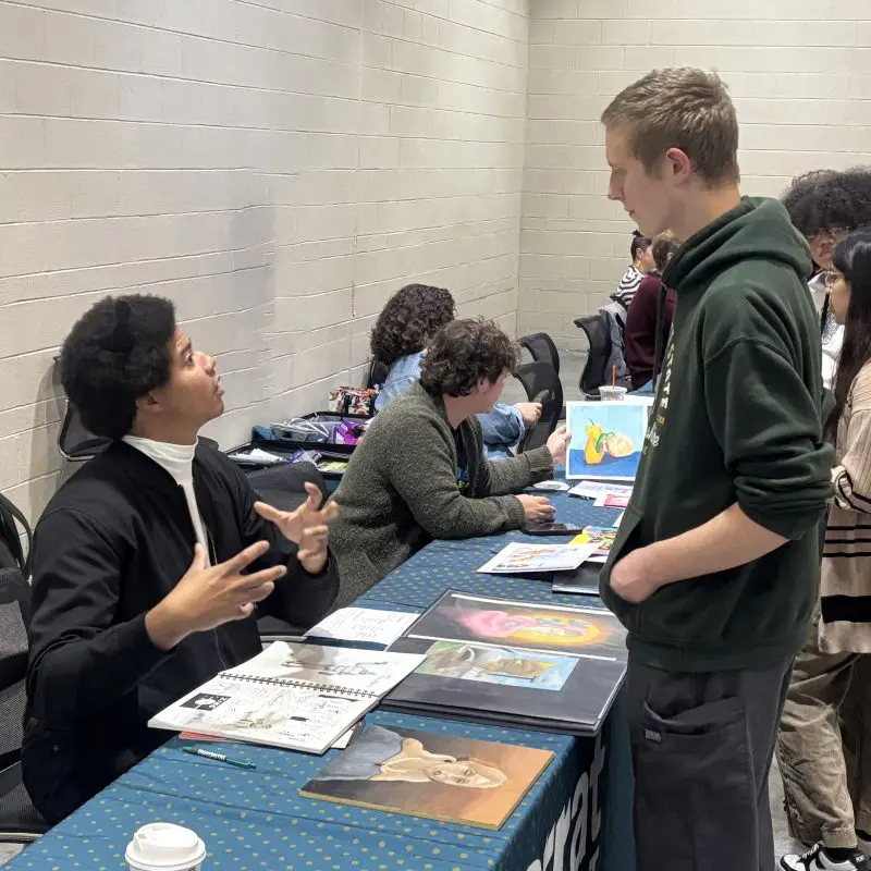 student at college fair having his portfolio reviewed
