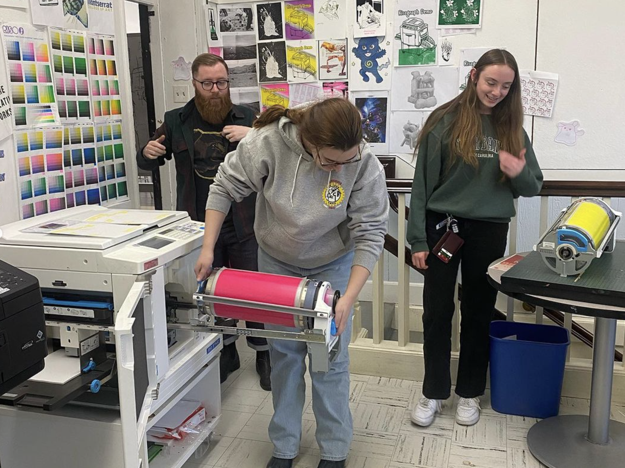 three people using a risograph printer
