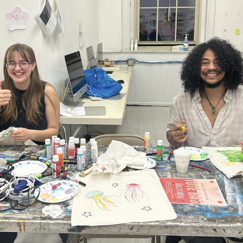 smiling students painting totebags