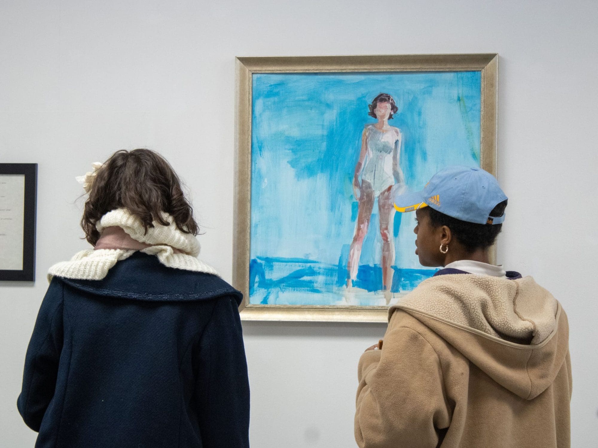 two people looking at a painting in a gallery