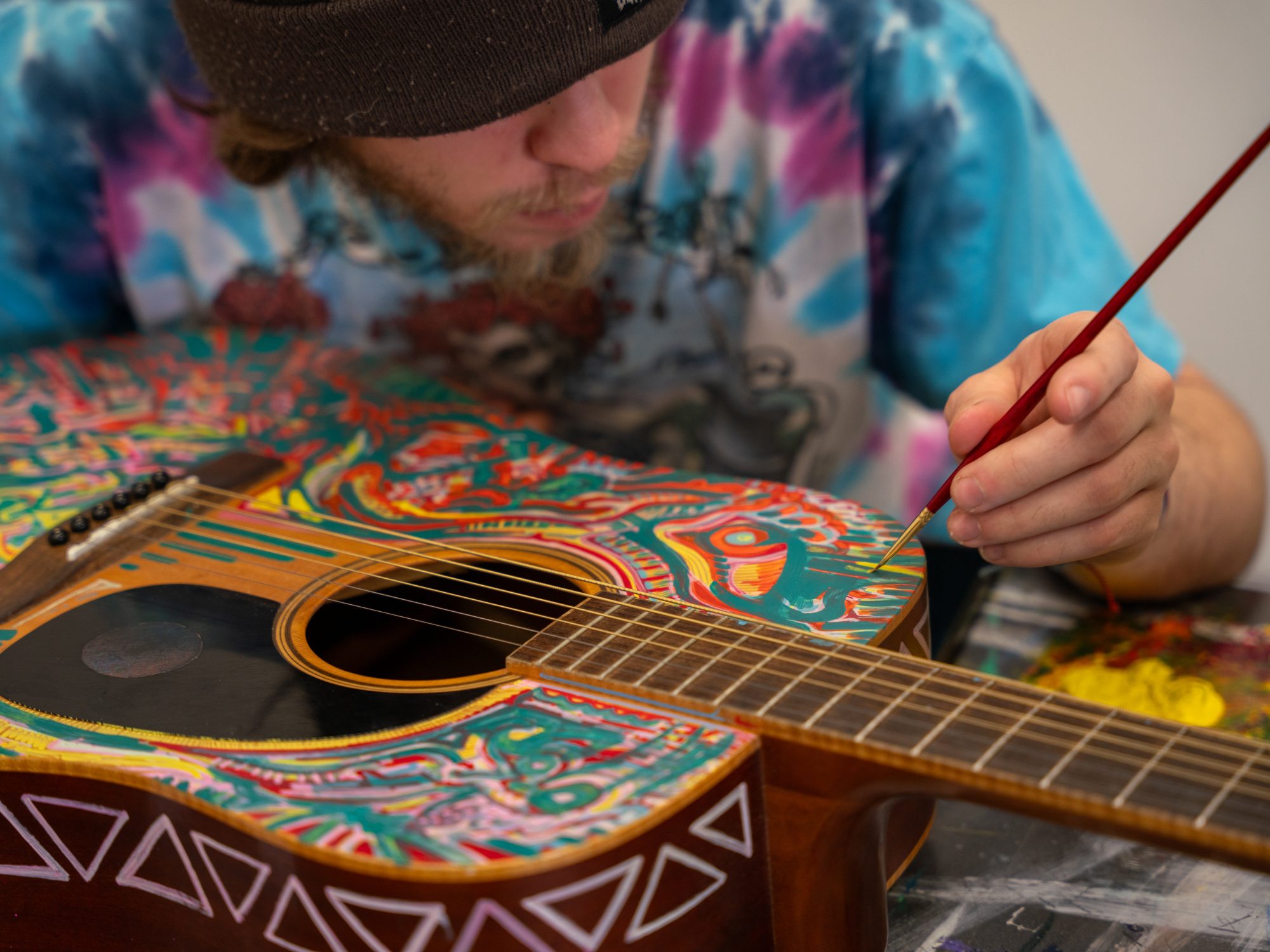 Person painting an acoustic guitar